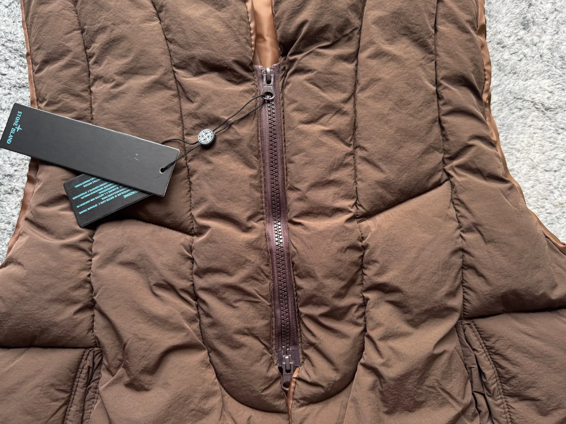 P280 Stone Island 25Fw Stone Island Linear Split Silhouette Cotton-Filled Deconstructed Waistcoat Jacket Stone Island's 2025 Grand Offering The outer layer is made of high-quality wrinkled nylon fabric, and the inner layer is filled with high-comfort and warm velvet cotton. The filling amount is very sufficient and the overall clothing is very full. The upper body silhouette and warmth are well guaranteed. The front and rear split line design is simple without losing details. The double zipper puller zipper increases practicality. The short design is very suitable for trendy matching in all seasons. It is very effective whether it is paired with a sweatshirt or a jacket. The basic black and chocolate brown meet the requirements of jumping in color and being versatile. It is a powerful tool for matching lazy suits when going out on the street. The classic emblem armband of Stone Island highlights the brand tension. It is first released on the entire network. Manufactured by a large factory. Complete with three-label accessories. Same style for men and women. Color: brown/black Size: m～xl